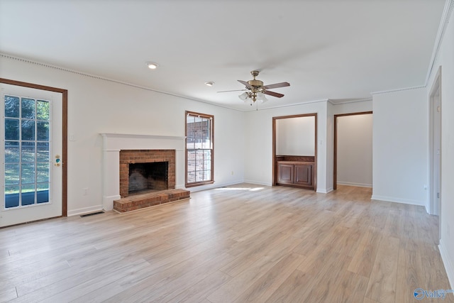 unfurnished living room with light hardwood / wood-style flooring, a wealth of natural light, a brick fireplace, and ceiling fan