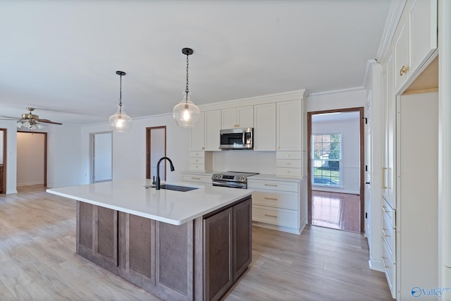 kitchen featuring appliances with stainless steel finishes, white cabinetry, a kitchen island with sink, and light hardwood / wood-style floors