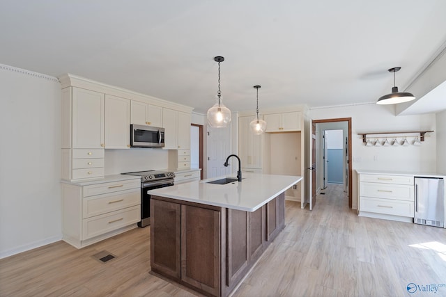 kitchen featuring hanging light fixtures, a kitchen island with sink, light wood-type flooring, sink, and stainless steel appliances