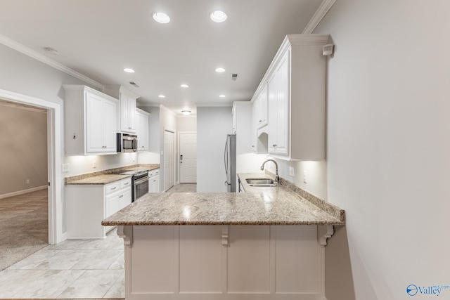 kitchen with appliances with stainless steel finishes, a sink, a peninsula, white cabinetry, and ornamental molding