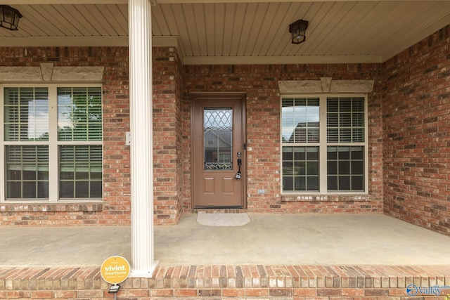 property entrance with a porch and brick siding
