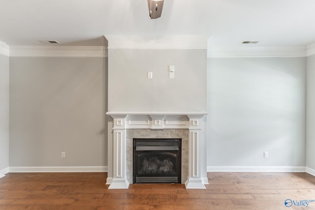 unfurnished living room featuring visible vents, ornamental molding, wood finished floors, and a tiled fireplace