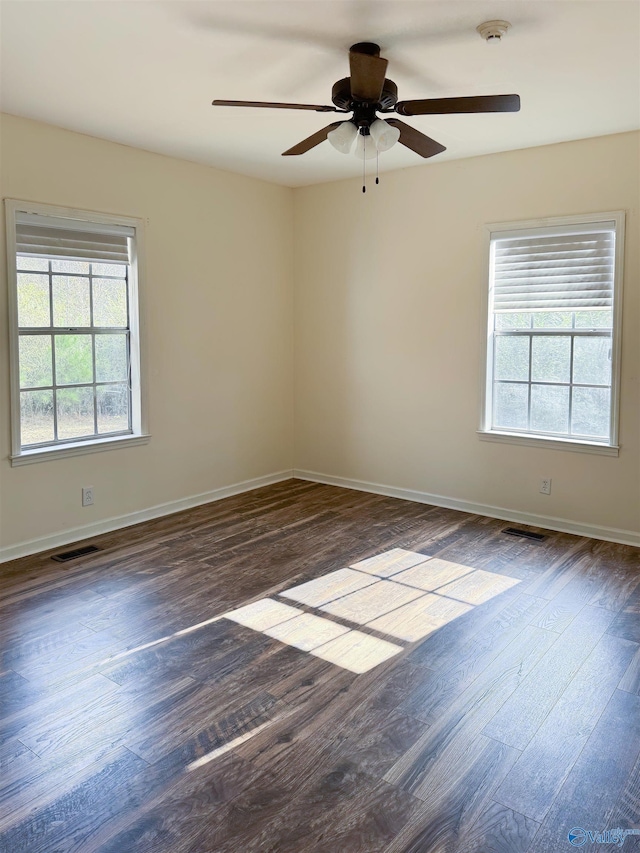 spare room with dark hardwood / wood-style flooring, a wealth of natural light, and ceiling fan