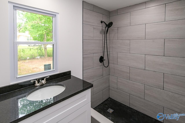 bathroom featuring tiled shower, vanity, and a healthy amount of sunlight