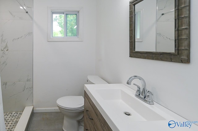 bathroom featuring vanity, a tile shower, and toilet