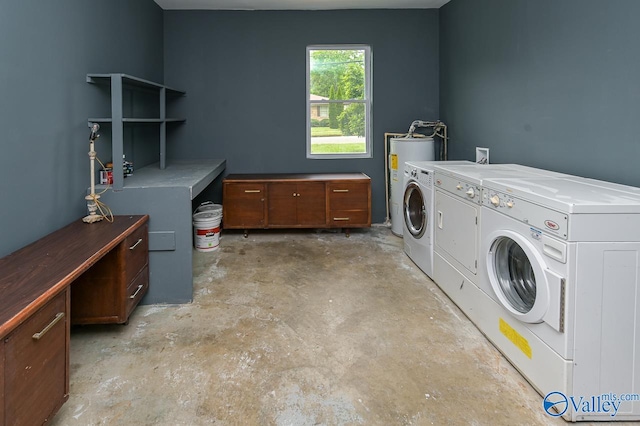 laundry area featuring water heater, cabinets, and washer and clothes dryer