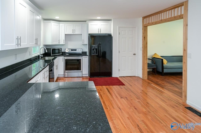 kitchen with light hardwood / wood-style floors, appliances with stainless steel finishes, white cabinets, and sink