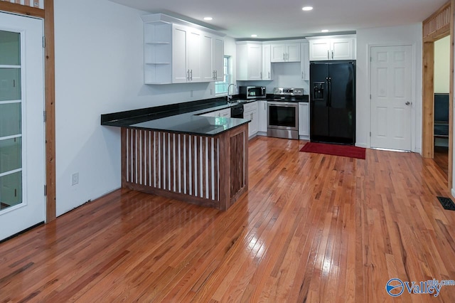 kitchen with sink, light hardwood / wood-style flooring, stainless steel appliances, and white cabinets