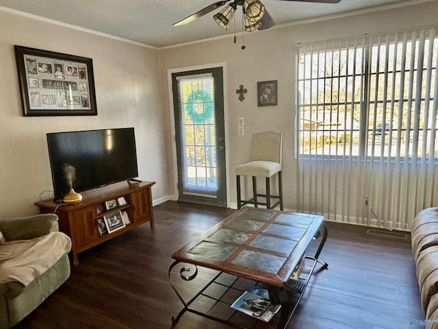 living area with a ceiling fan, crown molding, baseboards, and wood finished floors