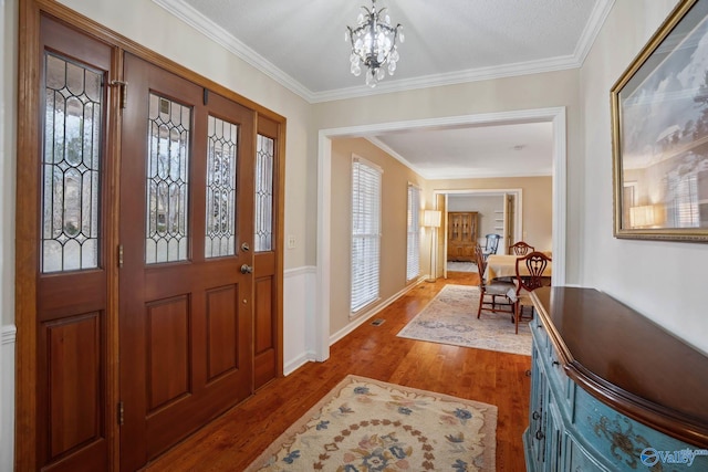 foyer with hardwood / wood-style floors, a notable chandelier, and ornamental molding