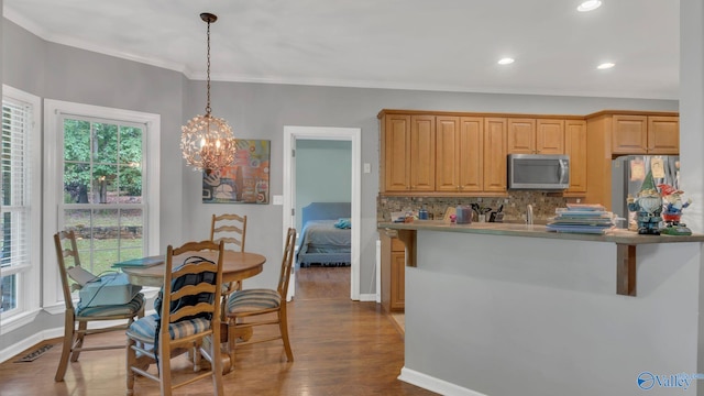 11266 Maggie Lou Dr, Tanner, AL 35671 - kitchen with stainless steel appliances, crown molding, dark wood finished floors, decorative light fixtures, and tasteful backsplash