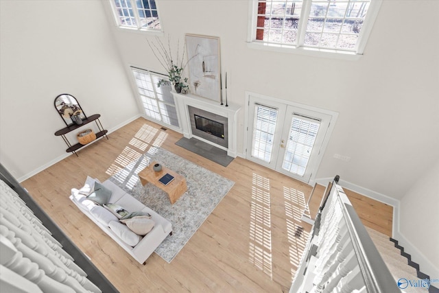 living room featuring french doors, a towering ceiling, and wood-type flooring