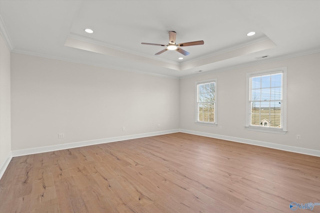 spare room with a tray ceiling, crown molding, light hardwood / wood-style flooring, and ceiling fan