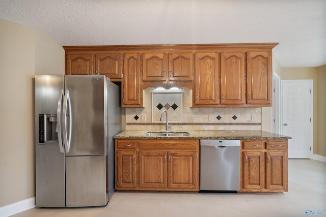 kitchen featuring sink, appliances with stainless steel finishes, backsplash, light stone countertops, and a textured ceiling