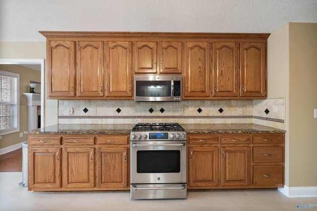 kitchen featuring dark stone countertops, decorative backsplash, a textured ceiling, and appliances with stainless steel finishes