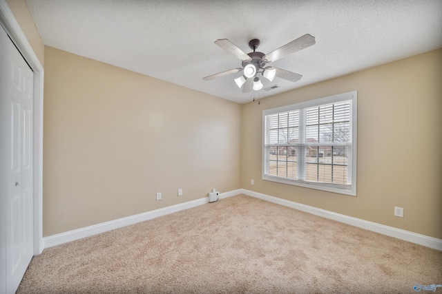 carpeted spare room with ceiling fan and a textured ceiling