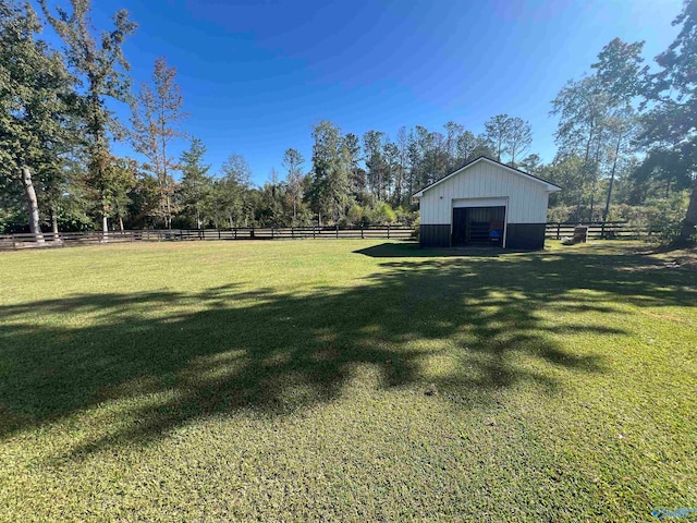 view of yard with a garage, a rural view, and an outdoor structure