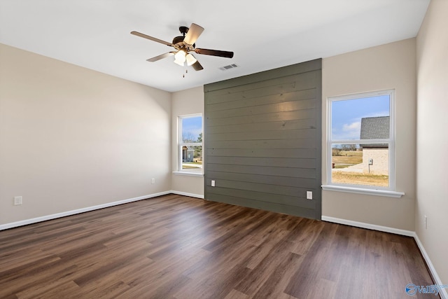 spare room with visible vents, baseboards, a ceiling fan, and dark wood finished floors