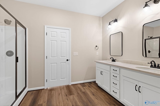 bathroom featuring a shower stall, baseboards, a sink, and wood finished floors