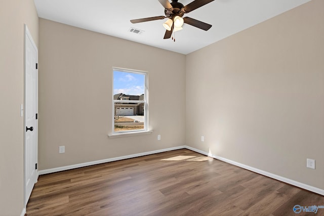 spare room featuring visible vents, ceiling fan, wood finished floors, and baseboards