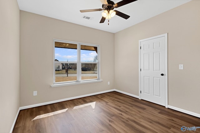 empty room with dark wood-type flooring, baseboards, a ceiling fan, and visible vents