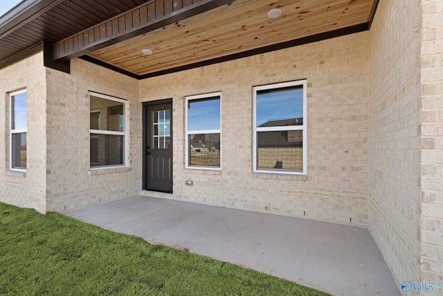 view of exterior entry featuring a patio area and brick siding