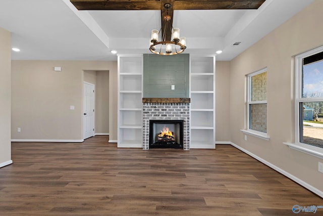 unfurnished living room featuring a lit fireplace, an inviting chandelier, baseboards, and dark wood-style flooring