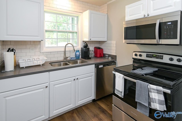 kitchen with white cabinets, decorative backsplash, dark wood-type flooring, stainless steel appliances, and a sink