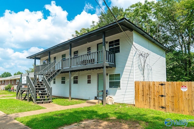 view of front of property featuring a front lawn, stairway, and fence