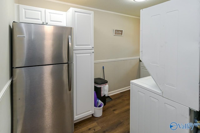 kitchen featuring dark wood-style floors, a wainscoted wall, freestanding refrigerator, white cabinets, and stacked washing maching and dryer