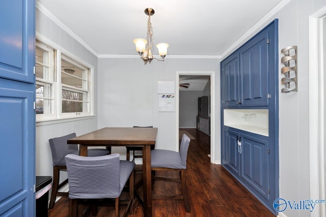 dining space featuring dark wood-type flooring, an inviting chandelier, and ornamental molding