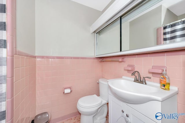 full bathroom with toilet, tile walls, wainscoting, and vanity