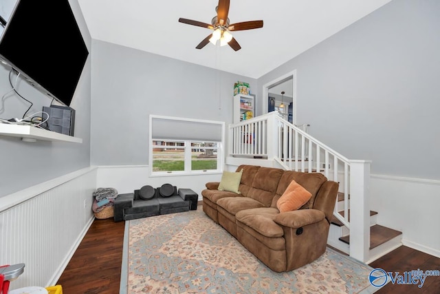 living area featuring ceiling fan, stairway, wood finished floors, and wainscoting