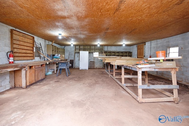 interior space with a workshop area, unfinished concrete floors, and concrete block wall