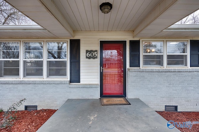 doorway to property with crawl space and brick siding