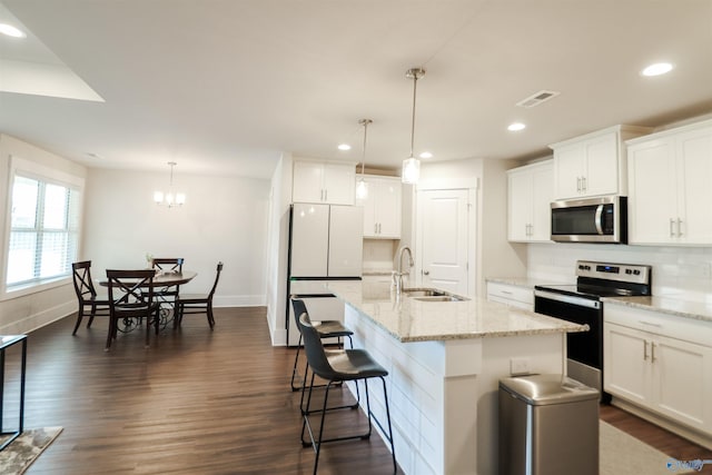 kitchen with white cabinetry, an island with sink, hanging light fixtures, and appliances with stainless steel finishes