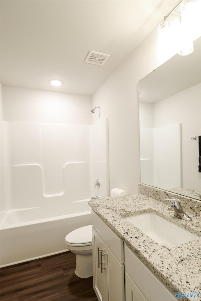 full bathroom with hardwood / wood-style flooring, vanity, shower / bathtub combination, and toilet