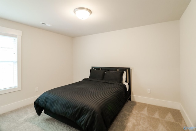 bedroom featuring light carpet and multiple windows