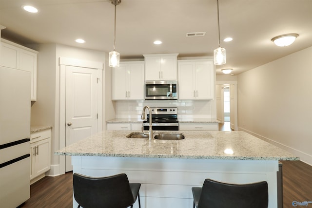 kitchen with appliances with stainless steel finishes, sink, pendant lighting, a center island with sink, and white cabinets