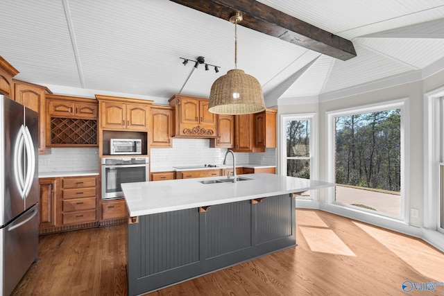 kitchen with brown cabinets, decorative light fixtures, stainless steel appliances, light countertops, and a sink