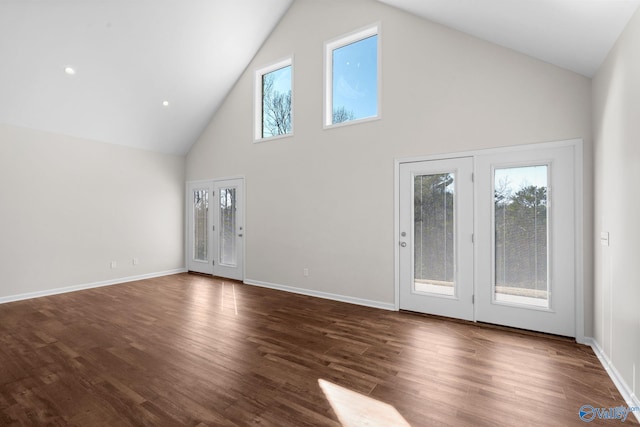 unfurnished living room featuring dark wood-style floors, baseboards, and high vaulted ceiling