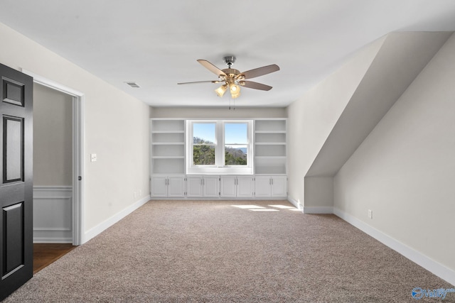 bonus room featuring carpet, built in features, ceiling fan, and baseboards