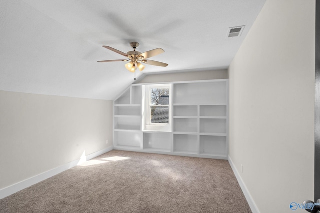 additional living space with carpet floors, visible vents, vaulted ceiling, ceiling fan, and baseboards
