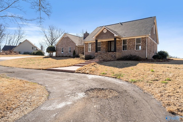 view of front of property with a front yard, a chimney, and brick siding