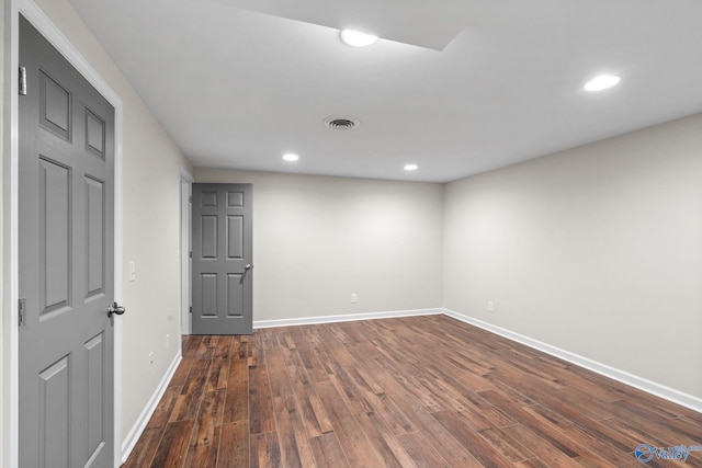 empty room with dark wood-style floors, baseboards, visible vents, and recessed lighting