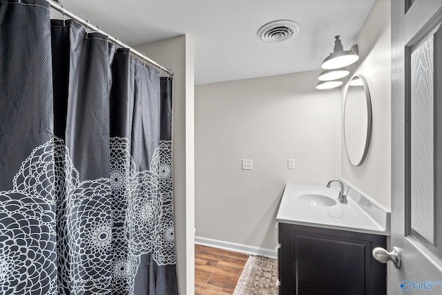 full bathroom with visible vents, vanity, baseboards, and wood finished floors