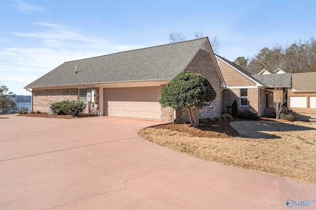 view of front of house with concrete driveway, brick siding, roof with shingles, and an attached garage