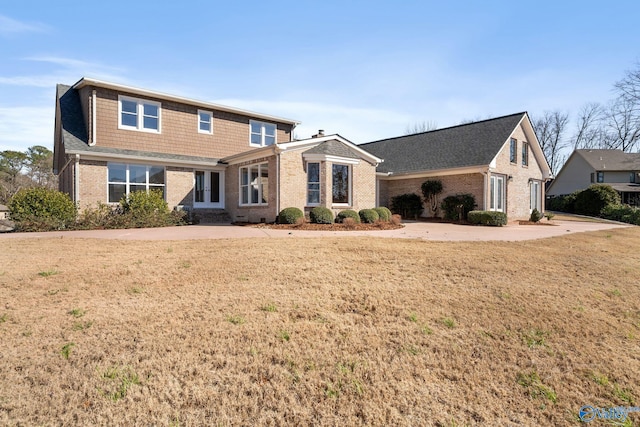 traditional-style home featuring a front lawn and brick siding
