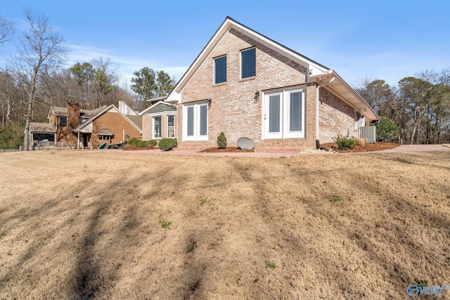back of house featuring a lawn and brick siding