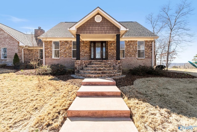 view of front facade with a front yard, brick siding, and roof with shingles